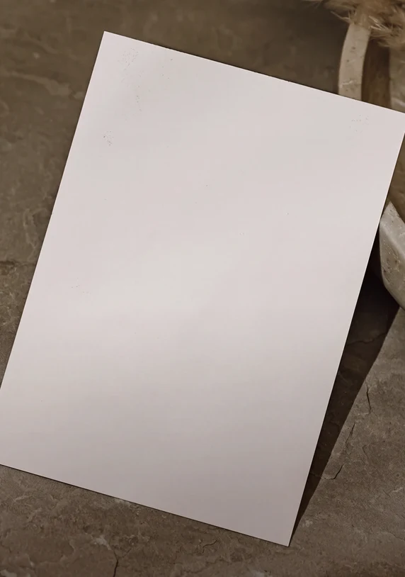 Tarjeta regalo blanca de Pluma con textos en inglés y alemán sobre fondo color piedra.