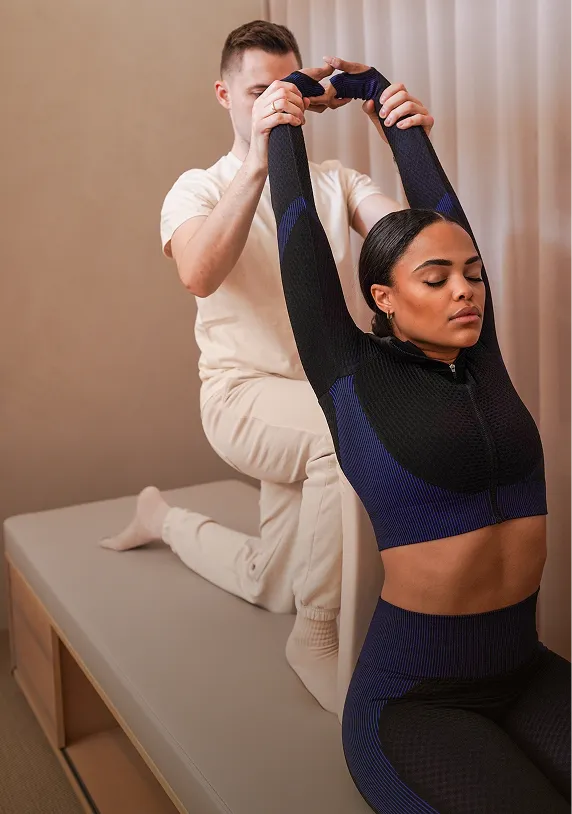 Una mujer en ropa deportiva recibe una sesión de Assisted Stretch.