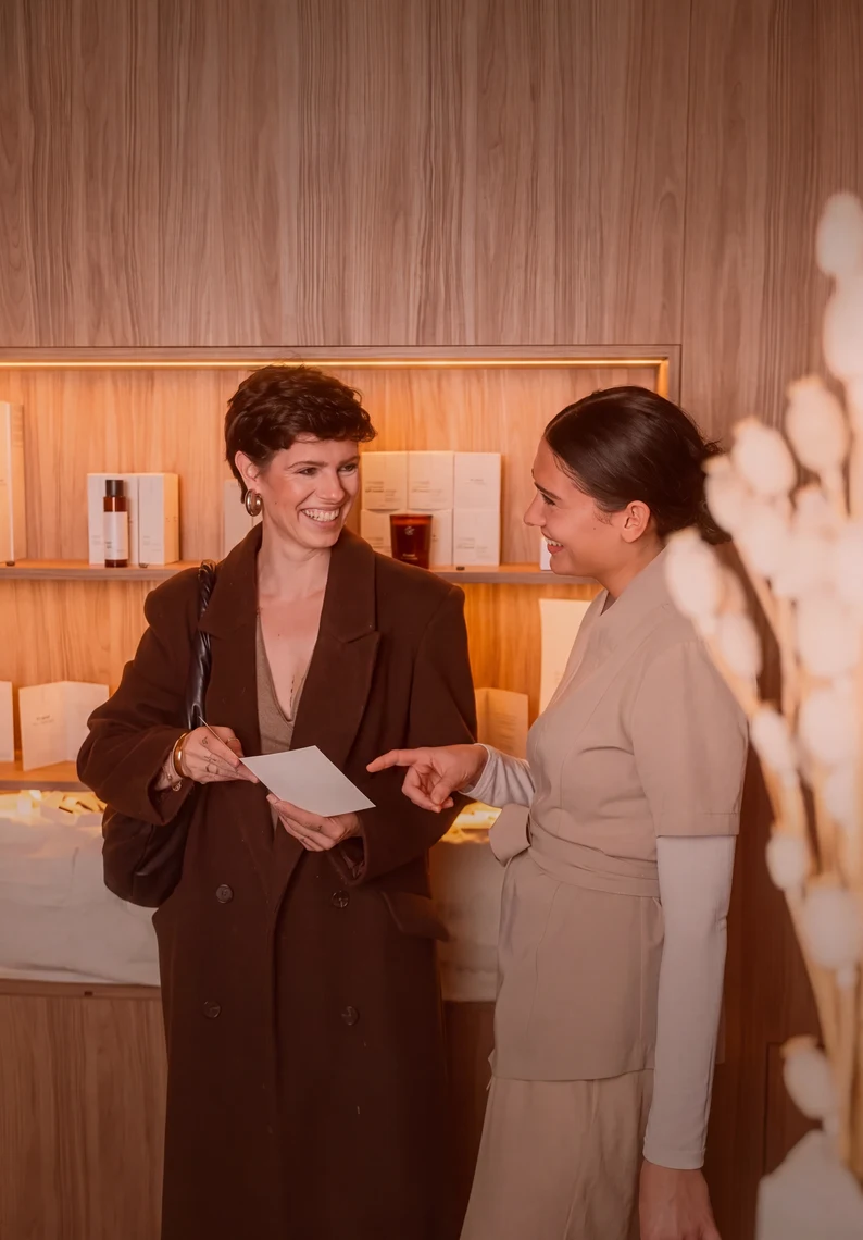 Una mujer que ha comprado una tarjeta regalo de masaje Pluma y recibe el asesoramiento de una Expert en masaje.