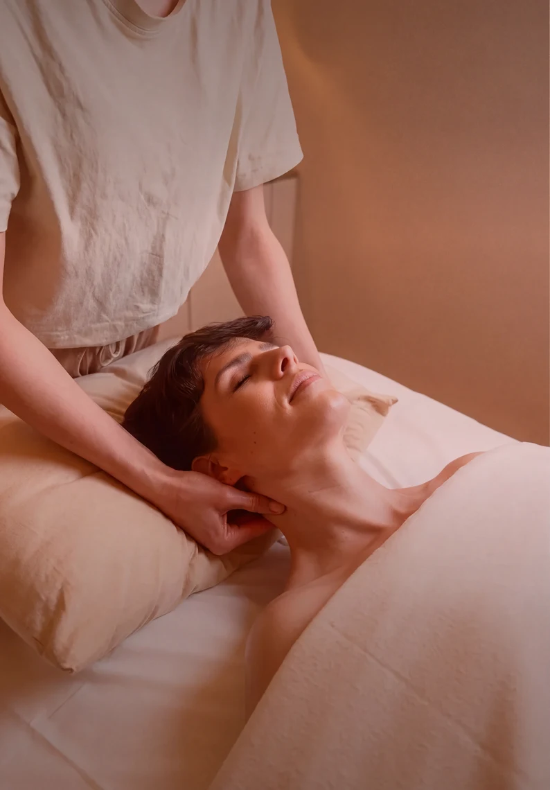 Una mujer se relaja mientras otra persona le da un masaje wellness.