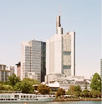 Vista de rascacielos en Frankfurt y edificios junto al Meno bajo un cielo despejado.