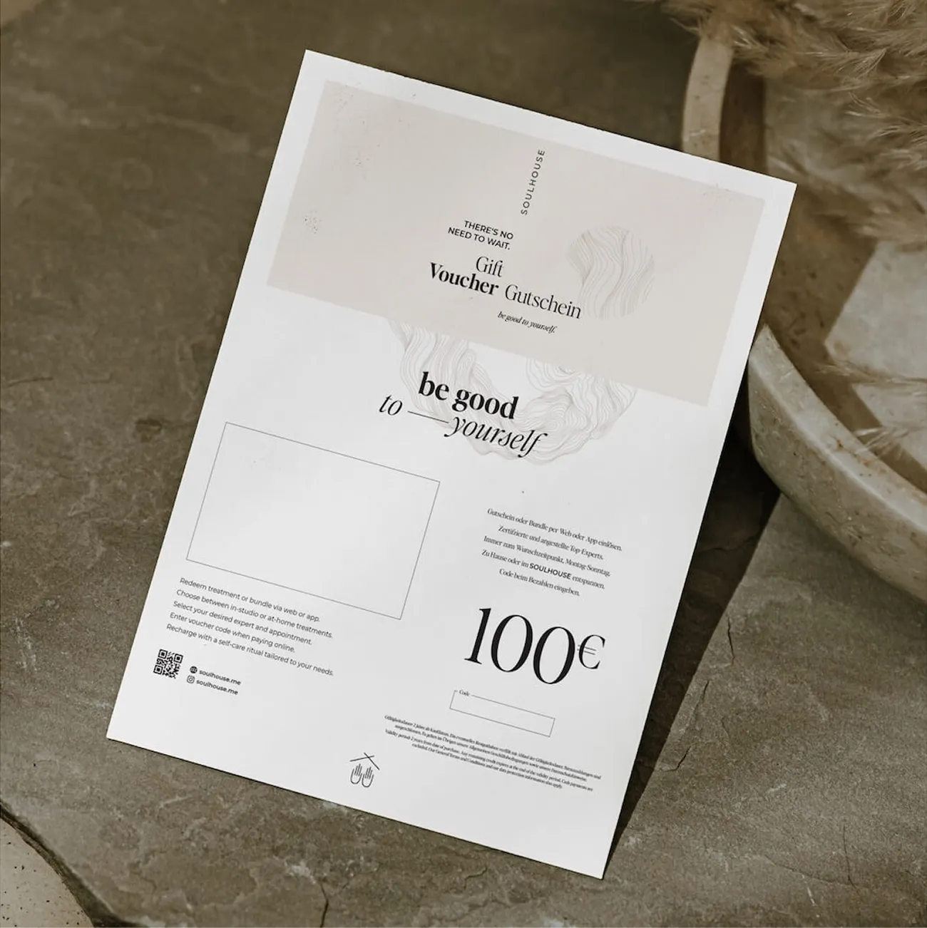 Tarjeta regalo de Pluma por valor de US$ 100 con la inscripción 'be good to yourself' sobre fondo de piedra.