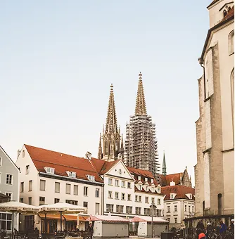 Edificios históricos con torres de iglesia puntiagudas y tejados rojos bajo un cielo despejado en una ciudad europea.