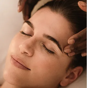 Una mujer se relaja con los ojos cerrados durante un relajante masaje wellness.