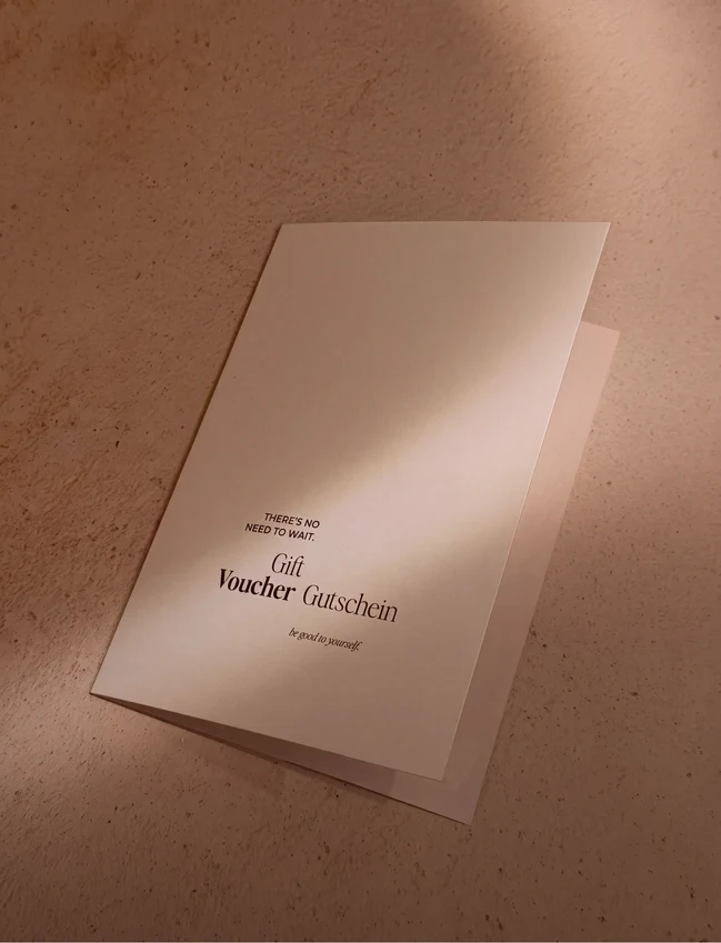 Elegante tarjeta regalo de PLUMA con el texto 'THERE'S NO NEED TO WAIT. Gift Voucher Gutschein be good to yourself.' sobre fondo beige.